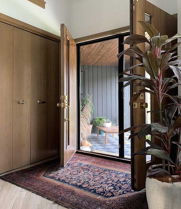 entranceway with large wooden doors and carpet leading outside