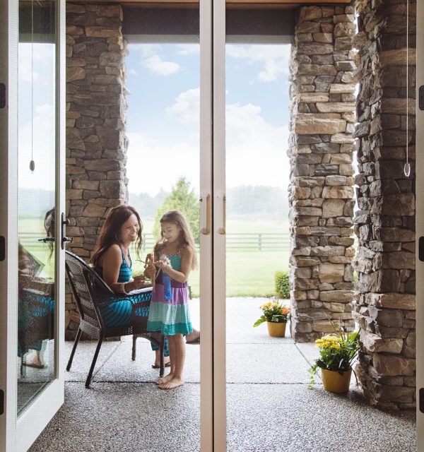 a woman and girl on an enclosed patio seen through a sliding screen door